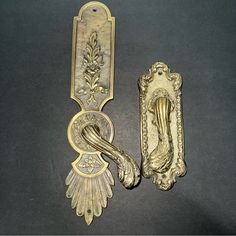 two antique brass door handles with designs on them, one has a handle and the other is