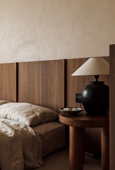 a bed sitting next to a table with a lamp on top of it