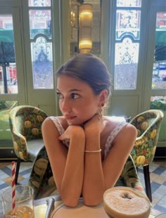 a woman sitting at a table with her hands on her chin and looking off to the side