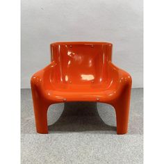 an orange plastic chair sitting on top of a floor