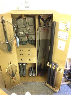 an open cabinet filled with lots of different types of fishing gear and equipment on top of it