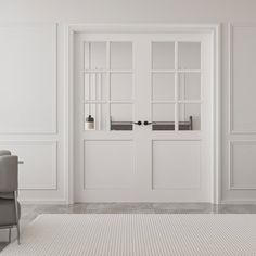 an empty white room with two chairs and a large rug in front of the door