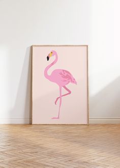 a pink flamingo standing on top of a hard wood floor next to a white wall