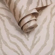 a roll of tape sitting on top of a wallpaper covered in silver and beige designs