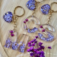 purple flowers and clear acrylic letters sitting on a wooden table next to each other