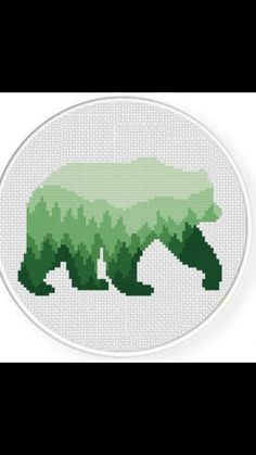 a cross stitch bear with green grass on it's back, in the shape of a circle