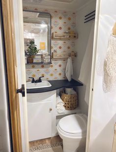 a white toilet sitting next to a sink in a bathroom under a mirror on top of a wall