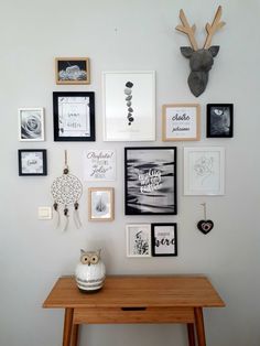 a wooden table sitting in front of a wall filled with pictures and framed art on it