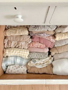 an open drawer filled with pillows and blankets