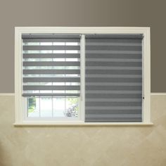 a bathroom with a toilet, sink and window covered in grey roman blind shades on the windowsill