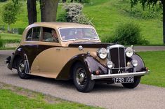 an old car is parked on the side of the road in front of some trees