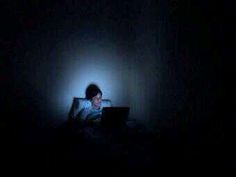 a person sitting in the dark using a laptop computer