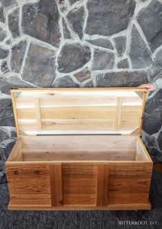 an empty wooden box sitting in front of a stone wall