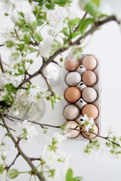 an egg carton filled with eggs sitting on top of a table next to flowers