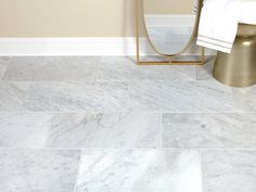 a bathroom with white marble floors and gold accents on the walls, along with a mirror