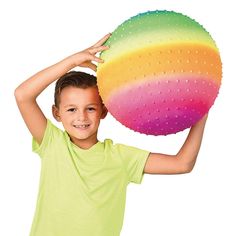 a young boy holding a large colorful ball in his right hand and smiling at the camera