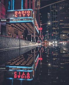 the radio city music hall sign is reflecting in the water