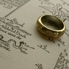 a gold ring sitting on top of an open book with writing all over the pages