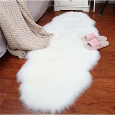 a pair of pink slippers sitting on top of a white fur rug next to a bed