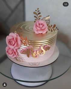 a cake decorated with pink flowers and gold lettering