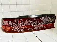 a red and black box sitting on top of a white tile floor next to a wall