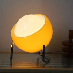 a yellow lamp sitting on top of a wooden table next to a white light bulb