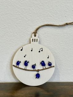 a wooden ornament with blue birds and musical notes hanging from it's side