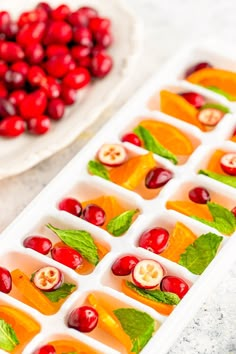 cranberries and orange slices are arranged in an ice tray