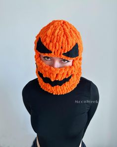 a man wearing an orange knitted pumpkin mask