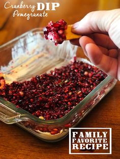 a person holding a spoon with cranberry dip on it in a casserole dish