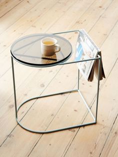 a glass table with a magazine on it and a cup of coffee next to it