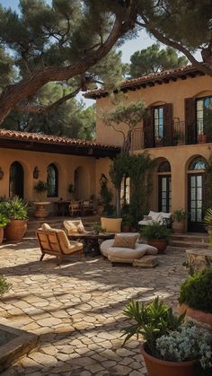 a patio with chairs and potted plants in front of a large house that has many windows