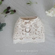 a wedding ring sits on top of a white lace purse next to flowers and greenery