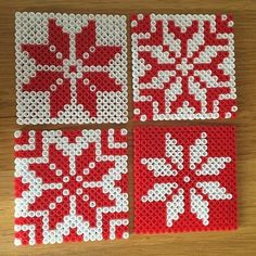 four pieces of red and white perler bead art on a wooden table top