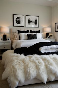 a white bed topped with lots of pillows next to two framed pictures on the wall