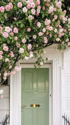 a green door with pink flowers growing over it