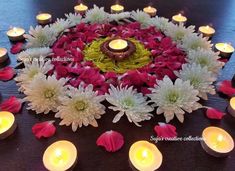 flowers and candles are arranged in the shape of a flower on a table with petals