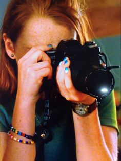 a woman taking a photo with a camera in front of her face and wearing bracelets