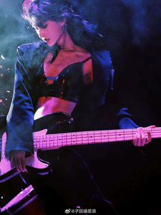 a woman playing a guitar on stage at a concert