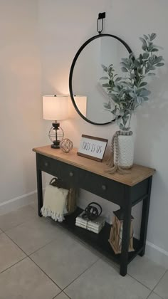 a table with a mirror, lamp and vase on it