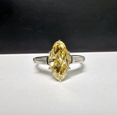 a fancy yellow diamond ring sitting on top of a table