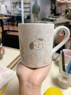 a person holding up a coffee cup with drawings on it