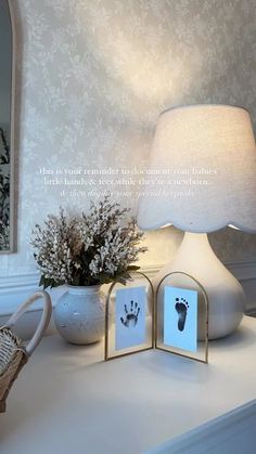 a table with a lamp and two hand prints on the front of it, next to a basket full of baby's footprints