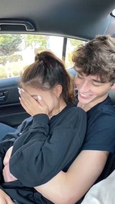 a man and woman sitting in the back seat of a car, one is holding her head