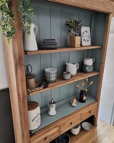 a wooden shelf filled with cups and vases