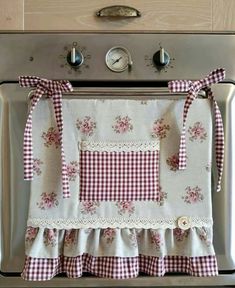 a kitchen stove with a red and white checkered apron hanging on it's side