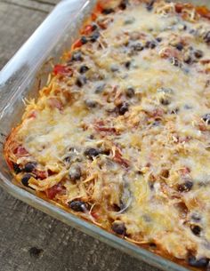 a casserole dish with black olives, cheese and meat in it on a wooden table