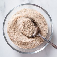 a glass bowl filled with oatmeal next to a spoon on top of a white counter