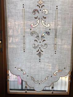 a window with an embroidered design on the side and some beads hanging from it's sides