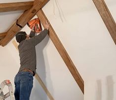 a man is working on the ceiling in his house with a drill and an electric saw